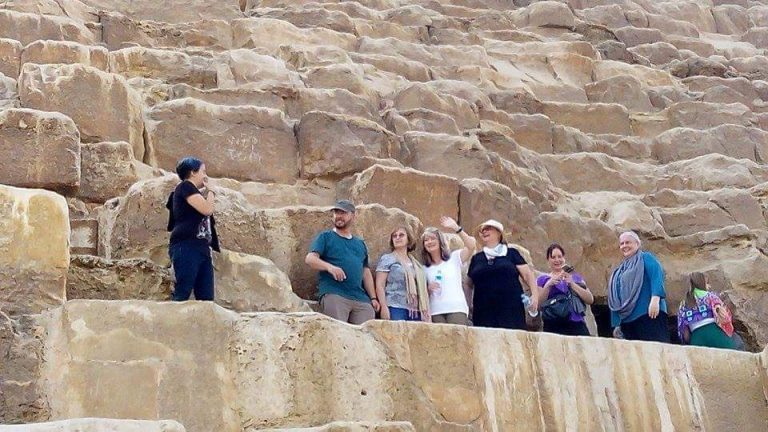 A group of 8 people standing standing on the side of the Great Pyramid ready to go inside.
