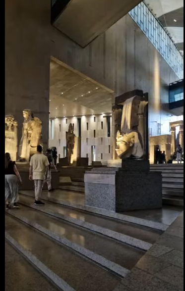 The Grand Staircase at the Grand Egyptian Museum (GEM) in Cairo, with ancient statues lining the steps