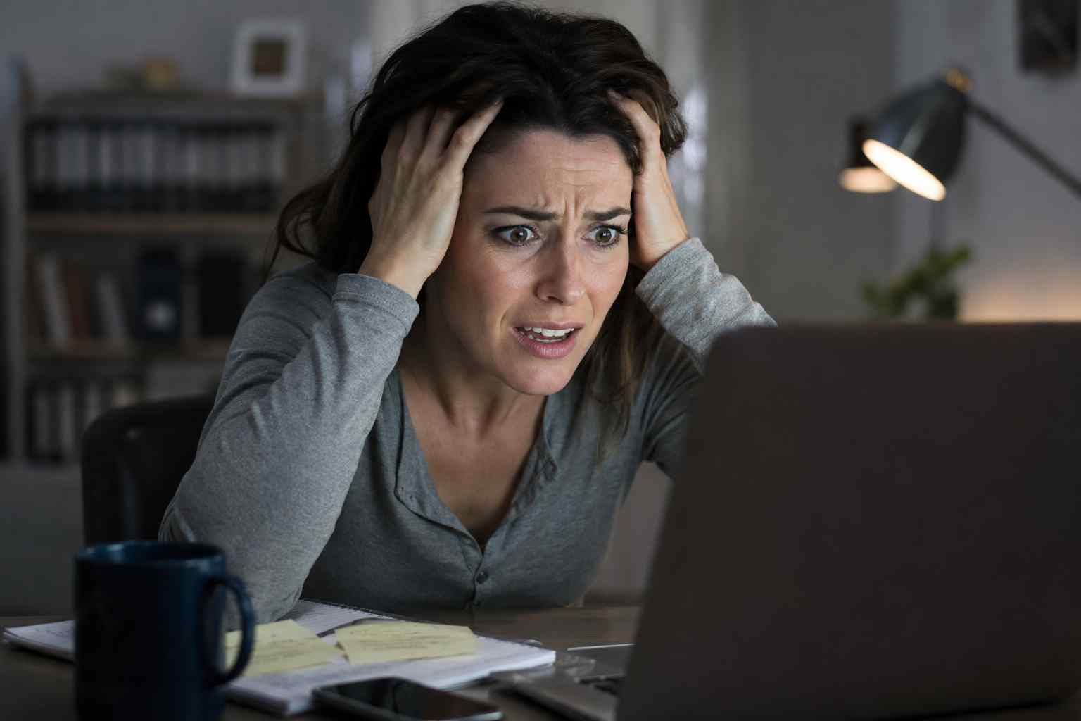 woman sitting at computer screen, holding her head in her hands, obviously frustrated she can't find what she is looking for.