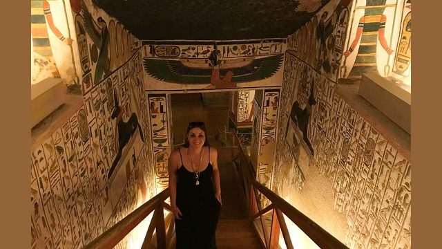 Amazing colour on the walls of this tomb in Valley of Kings, Luxor young lady ascending stairway from tomb. Walls on either side and ceiling colourfully decorated with carvings