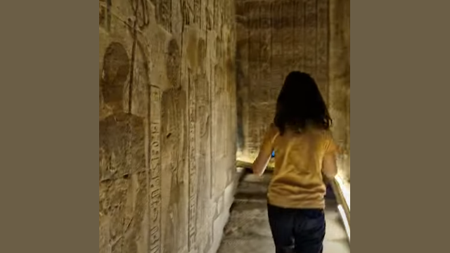 Dendera is a place of fascination for all ages and a place of wonder especially for adventurous children such as this 9 year old A young boy in a yellow t-Shirt ascending the worn steps of the spiral staircase at Dendera - surrounding walls covered in carvings